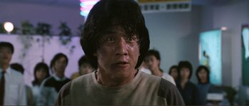 Movie still from “Police Story” (1985), directed by Jackie Chan – A person with a crowd in the background; Close Up shot, Low angle