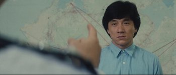 Movie still from “Police Story 2” (1988), directed by Jackie Chan – A man in a blue dress shirt is pointing at a map; Close Up shot, Over the shoulder angle