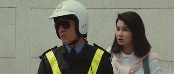Movie still from “Police Story 2” (1988), directed by Jackie Chan – A man in a police uniform next to a woman; Close Up shot, Over the shoulder angle