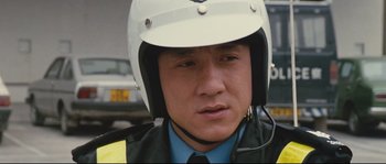 Movie still from “Police Story 2” (1988), directed by Jackie Chan – A police officer wearing a white helmet and a yellow jacket; Close Up shot, Low angle