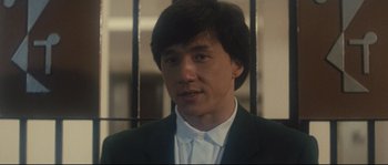 Movie still from “Police Story 2” (1988), directed by Jackie Chan – A person wearing a suit and tie; Close Up shot, Low angle