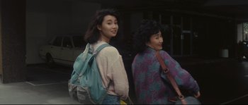 Movie still from “Police Story 2” (1988), directed by Jackie Chan – Two young women walking down a street with backpacks; Medium shot, High angle