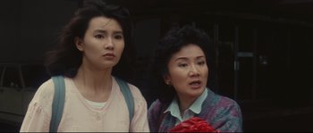 Movie still from “Police Story 2” (1988), directed by Jackie Chan – Two women standing next to each other in front of a building; Close Up shot, High angle