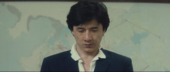 Movie still from “Police Story 2” (1988), directed by Jackie Chan – A person wearing a suit and tie; Close Up shot, Low angle