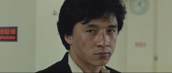 Movie still from “Police Story 2” (1988), directed by Jackie Chan – A person wearing a suit and tie; Close Up shot, High angle