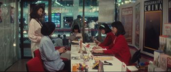 Movie still from “Police Story 2” (1988), directed by Jackie Chan – A group of people sitting at a table with papers; Wide shot, High angle