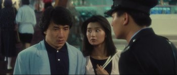 Movie still from “Police Story 2” (1988), directed by Jackie Chan – A group of people standing next to each other on the street; Close Up shot, Over the shoulder angle