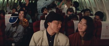 Movie still from “Police Story 2” (1988), directed by Jackie Chan – A man sitting on a bus wearing a hat; Medium shot, Over the shoulder angle