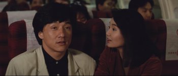 Movie still from “Police Story 2” (1988), directed by Jackie Chan – A man and a woman sitting next to each other on a train; Close Up shot, Over the shoulder angle