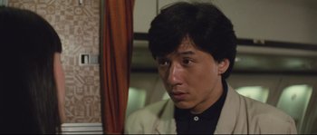 Movie still from “Police Story 2” (1988), directed by Jackie Chan – A man in a suit looking to his left; Close Up shot, Over the shoulder angle