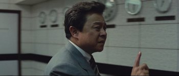 Movie still from “Police Story 2” (1988), directed by Jackie Chan – A person wearing a suit and tie; Close Up shot, Low angle