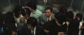 Movie still from “Police Story 2” (1988), directed by Jackie Chan – A group of people sitting in a train car; Medium shot, Overhead angle