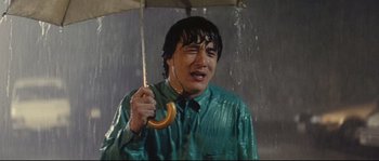 Movie still from “Police Story 2” (1988), directed by Jackie Chan – A man holding an umbrella while standing in the rain; Close Up shot, High angle