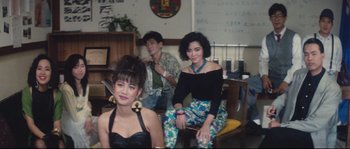 Movie still from “Police Story 2” (1988), directed by Jackie Chan – A group of people sitting in a living room together; Medium shot, High angle