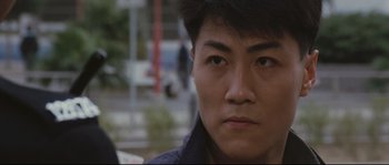 Movie still from “Police Story 2” (1988), directed by Jackie Chan – A person's face with a blurry background; Close Up shot, Low angle