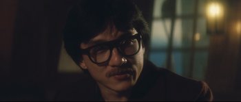 Movie still from “Police Story 2” (1988), directed by Jackie Chan – A man with a mustache wearing glasses and a suit; Close Up shot, Over the shoulder angle