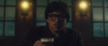 Movie still from “Police Story 2” (1988), directed by Jackie Chan – A man in a suit smoking a cigarette and holding a glass of wine; Close Up shot, Low angle