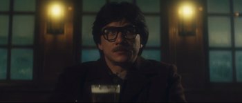 Movie still from “Police Story 2” (1988), directed by Jackie Chan – A man wearing glasses and a jacket is holding a glass; Close Up shot, Low angle