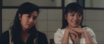 Movie still from “Police Story 2” (1988), directed by Jackie Chan – Two young women sitting next to each other in front of a window; Close Up shot, Over the shoulder angle
