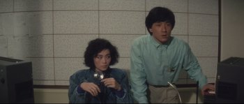 Movie still from “Police Story 2” (1988), directed by Jackie Chan – A man and a woman are standing next to each other; Medium shot, High angle