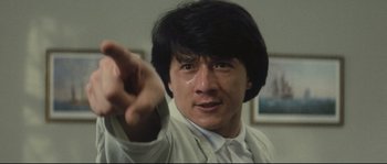 Movie still from “Police Story 2” (1988), directed by Jackie Chan – A person holding something up; Close Up shot, Low angle