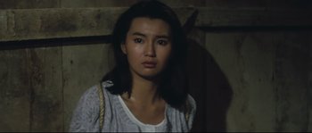 Movie still from “Police Story 2” (1988), directed by Jackie Chan – A woman with long dark brown hair wearing a white shirt; Close Up shot, High angle