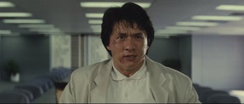 Movie still from “Police Story 2” (1988), directed by Jackie Chan – A person wearing a white shirt and jacket; Close Up shot, Low angle
