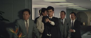 Movie still from “Police Story 2” (1988), directed by Jackie Chan – A group of men in suits and ties holding guns; Medium shot, Low angle