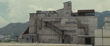 Movie still from “Police Story 2” (1988), directed by Jackie Chan – An old building with a staircase going up the side of it; Extreme Wide shot, High angle