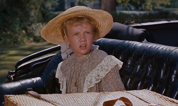 Movie still from “Pollyanna” (1960), directed by David Swift – A young girl sitting in a chair wearing a straw hat; Close Up shot, High angle