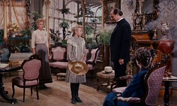 Movie still from “Pollyanna” (1960), directed by David Swift – A group of people sitting in a living room; Wide shot, Over the shoulder angle