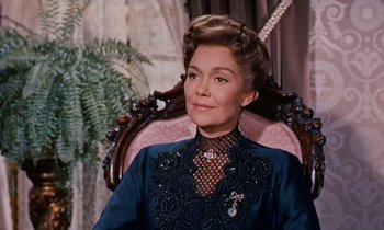 Movie still from “Pollyanna” (1960), directed by David Swift – A woman sitting in a chair wearing a blue dress; Close Up shot, Over the shoulder angle