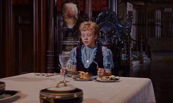 Movie still from “Pollyanna” (1960), directed by David Swift – A boy sitting at a dinner table with a plate of food in front of him; Medium shot, High angle
