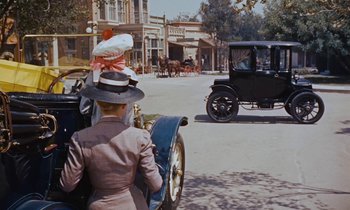 Movie still from “Pollyanna” (1960), directed by David Swift – A woman in a hat riding in a carriage down a street; Wide shot, High angle