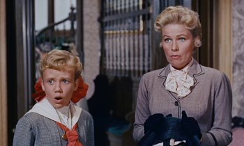 Movie still from “Pollyanna” (1960), directed by David Swift – A woman standing next to a young boy in front of a building; Close Up shot, Low angle