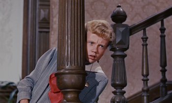 Movie still from “Pollyanna” (1960), directed by David Swift – A young boy leaning up against a railing; Medium shot, Low angle