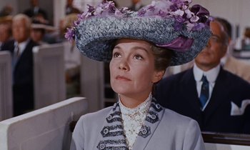 Movie still from “Pollyanna” (1960), directed by David Swift – A woman wearing a hat with purple flowers on top of her head; Close Up shot, Low angle