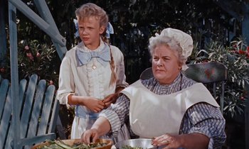Movie still from “Pollyanna” (1960), directed by David Swift – An older woman and a young girl preparing a meal; Medium shot, Over the shoulder angle