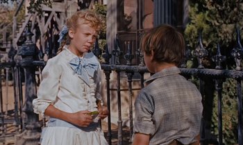 Movie still from “Pollyanna” (1960), directed by David Swift – A young boy and girl standing next to each other; Medium shot, Over the shoulder angle