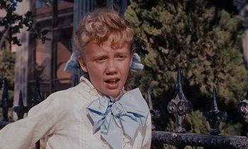 Movie still from “Pollyanna” (1960), directed by David Swift – A little girl wearing a blue bow tie and a white shirt; Close Up shot, Low angle