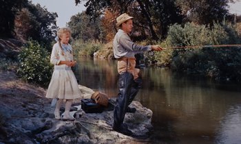 Movie still from “Pollyanna” (1960), directed by David Swift – A man and a woman fishing in a river; Wide shot, High angle