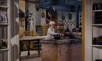 Movie still from “Pollyanna” (1960), directed by David Swift – An old woman in a kitchen preparing a meal; Wide shot, High angle