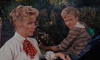 Movie still from “Pollyanna” (1960), directed by David Swift – Two women are sitting in a car and one of them is holding a steering wheel; Close Up shot, High angle