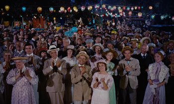 Movie still from “Pollyanna” (1960), directed by David Swift – A large group of people wearing hats and holding hands; Wide shot, High angle