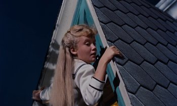Movie still from “Pollyanna” (1960), directed by David Swift – A woman in white shirt and long blonde hair on top of a roof; Medium shot, Low angle