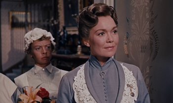 Movie still from “Pollyanna” (1960), directed by David Swift – An older woman in a victorian dress with a young man in the background; Close Up shot, Over the shoulder angle