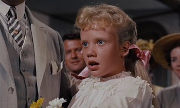 Movie still from “Pollyanna” (1960), directed by David Swift – A young girl in a white dress with a pink ribbon around her neck; Close Up shot, Low angle