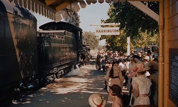 Movie still from “Pollyanna” (1960), directed by David Swift – A crowd of people standing next to a train on a train track; Wide shot, High angle