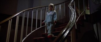 Movie still from “Poltergeist” (1982), directed by Tobe Hooper – A little girl wearing pajamas standing on a set of stairs; Wide shot, Low angle