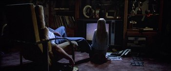 Movie still from “Poltergeist” (1982), directed by Tobe Hooper – Two people sitting in front of a television in a living room; Wide shot, High angle